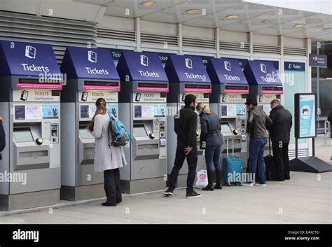 Passengers Using Automatic Ticket Machines To Purchase Train Tickets