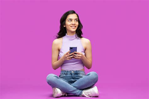 photo of cheerful girl holding phone with her hands looking up isolated over purple background