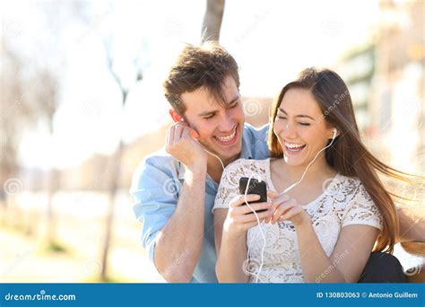 Joyful Couple Listening To Music From A Smartphone In A Pak Stock Image