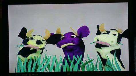 Three Cartoon Cows Standing In The Grass On A Flat Screen Tv With Their