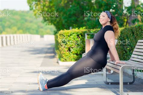 Portrait Of Active Happy Plump Woman Performs Exercises In The Park On