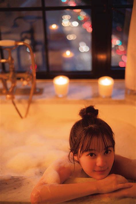 A Woman Laying In A Bathtub Next To Candles