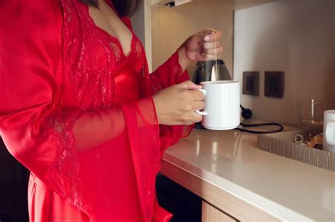 Una Mujer En Un Camisón De Seda Rojo Y Lujosas Batas Haciendo Té Caliente En La Cocina Por La