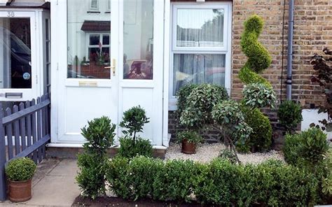 The Front Door Of A House With Potted Plants And Bushes In Front Of It
