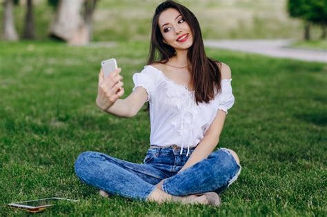 Chica Joven Sentada En Un Parque Haciéndose Una Autofoto Foto Gratis