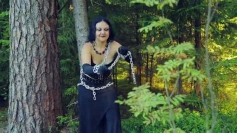An Angry Woman A Witch In Black Clothes In A Forest Tied With Chains