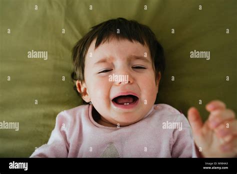 Portrait Of Crying Baby Girl Lying On Bed Stock Photo Alamy