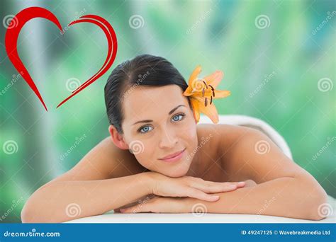composite image of beautiful brunette relaxing on massage table smiling at camera stock image