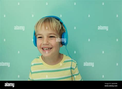 Happy Small 5s Kid Boy Wearing Blue Headphones Listening To Music