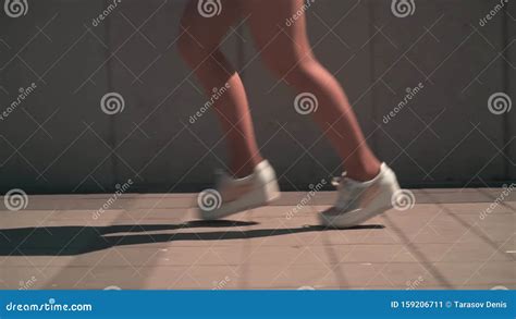 Close Up Of Female Legs A Girl With Tanned Legs In White Sneakers Runs