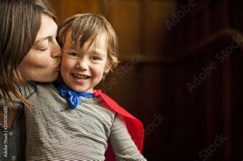 Mother Kissing Her Smiling Son At Home Stock Photo Adobe Stock