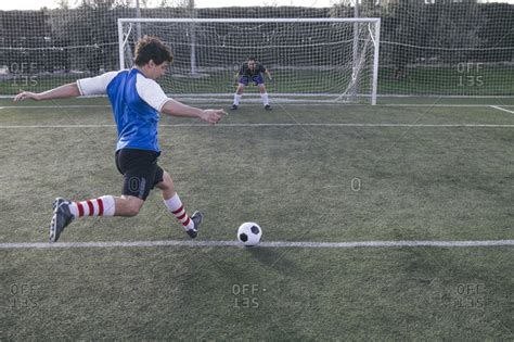 Soccer Player Kicking A Ball In Front Of A Goal With A Goalkeeper Stock