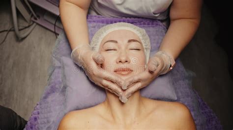 woman receiving facial massage in spa salon on massage table wellness body and skin care face