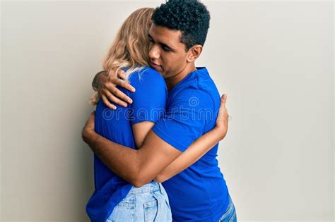 Young Interracial Couple Wearing Casual Clothes Hugging Oneself Happy