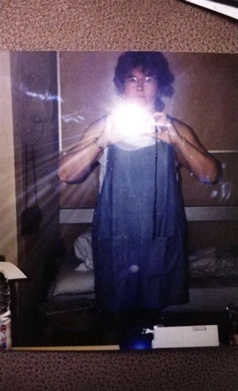 my mom on a cruise ship 1990 taking a selfie in the bathroom mirror wearing a blue jean onesie