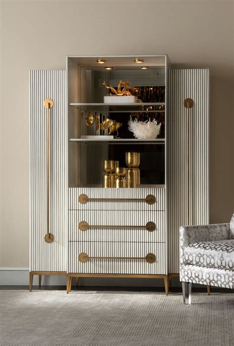 A White Cabinet With Gold Handles And Knobs In A Living Room Area Next