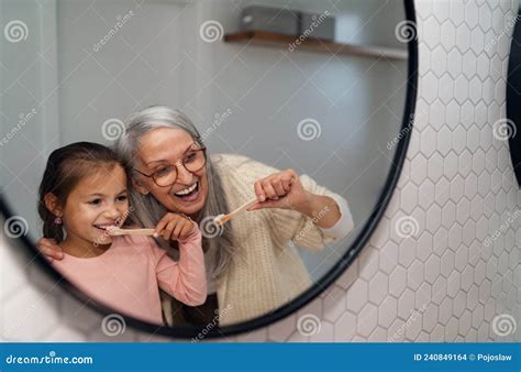 Grandmother With Granddaughter Standing Indoors In Bathroom Brusing