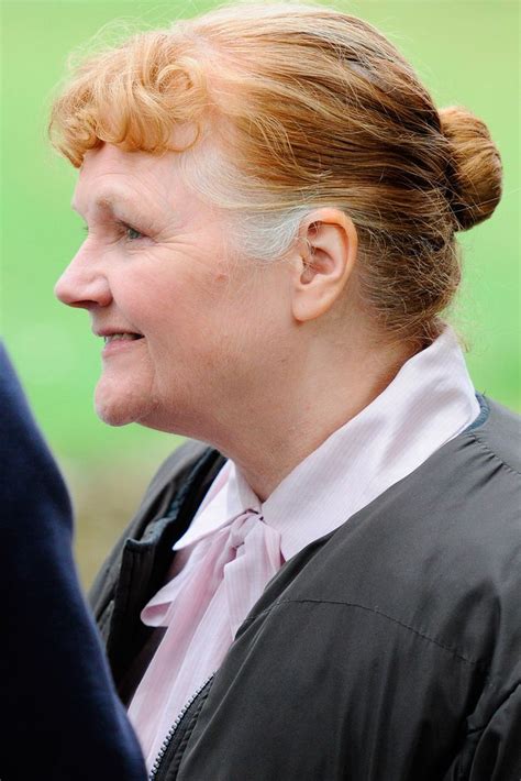 A Woman With Red Hair Is Wearing A Black Jacket And Has Her Head Turned To The Side