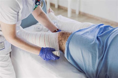 Nurse Wrapping Bandage Around Patients Leg In Hospital Bed Stock Photo