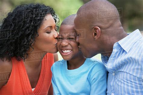 African American Parents Kissing Son S Cheeks Stock Photo Dissolve