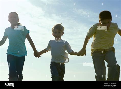 Three Children Running Holding Hands Backlit Stock Photo Alamy
