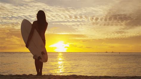 Surfer Woman In Silhouette Walking With Surfboard At Sunset On Tropical