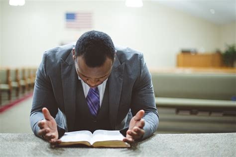 Africanamerican Male Praying With His Head Down Looking At The Bible At