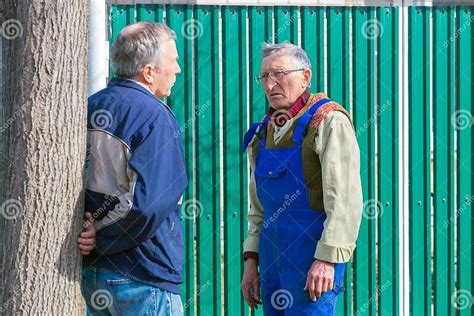 meeting of two mature neighbors at the gate of a rural house on a sunny