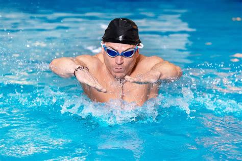 Giovane Del Nuotatore Muscolare In Berretto Nero Nella Piscina Eseguente Il Colpo Di Farfalla