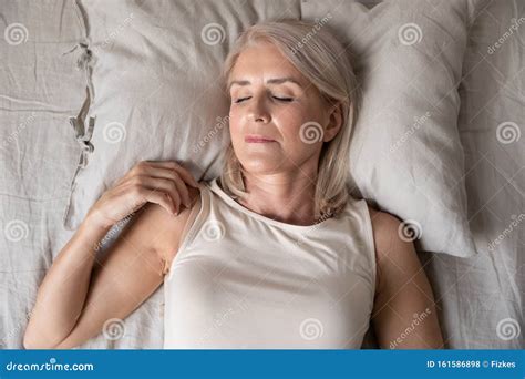 Healthy Serene Mature Woman Sleeping Alone In Bed Top View Stock Photo
