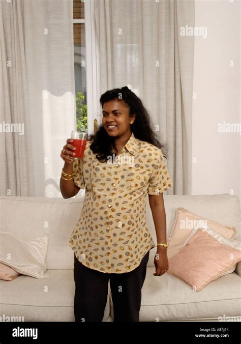 Pregnant Indian Sri Lankan Woman Standing In Room With Glass Of Orange