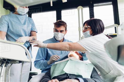 Dentist Looking Into Male Patients Mouth Dental Nurses Preparing