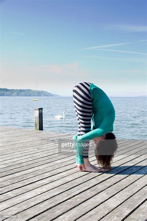 Side View Of Mature Woman On Pier By Ocean Bending Over Holding Ankles