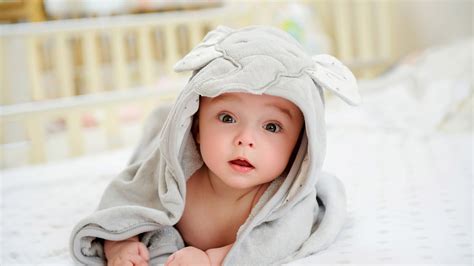 Cute Child Baby Is Lying Down On White Bed Covered With Elephant Face