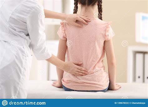 Chiropractor Examining Child With Back Pain In Clinic Stock Photo
