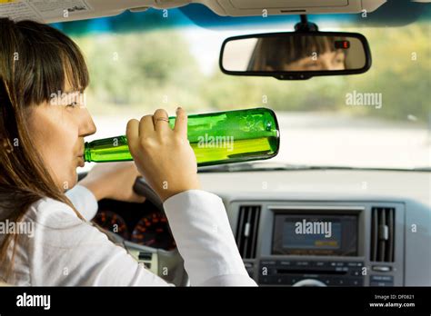 Intoxicated Woman Drinking And Driving As She Swigs Alcohol From The Bottle While Driving Down