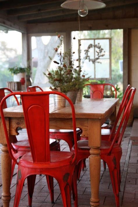 A red centerpiece adds lively energy to a glass dining table. Red Painted Metal Chairs - Interiors By Color