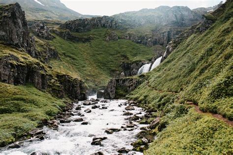 Beautiful Icelandic Landscape With Scenic Waterfall And Green Hills