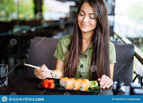 Portrait Of Beauty Girl Eating Sushi RollIn Cafe Healthy Japanese Food
