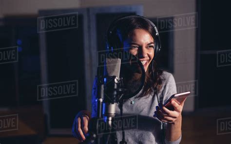Smiling Female Playback Singer With Microphone And Mobile Phone In