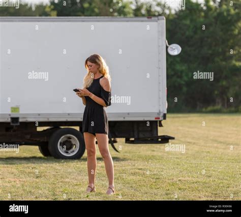 A Woman Standing In A Field Next To A Box Truck Outside Of An Event