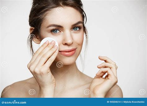 cute beautiful natural brunette girl cleaning face with cotton sponge smiling looking at camera