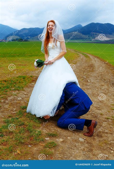 Groom Peeking Under His Bride Dress Funny Wedding Concept Stock