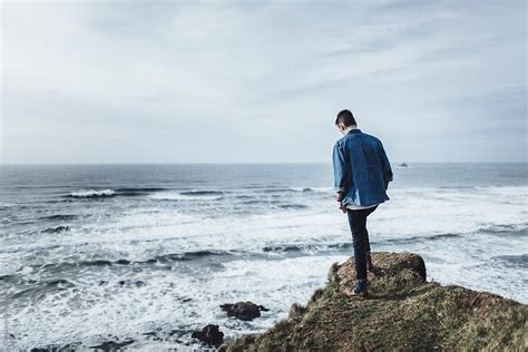 Young Man Standing On Cliff By The Ocean By Stocksy Contributor Evan