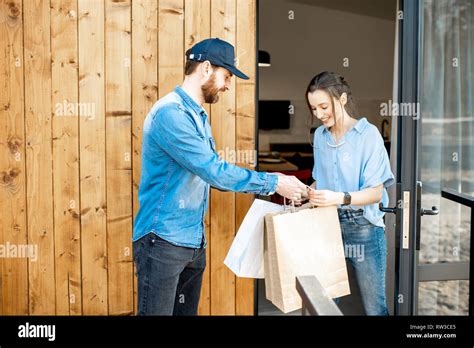 Delivery Man Bringing Some Goods Packaged In Paper Bags For A Young