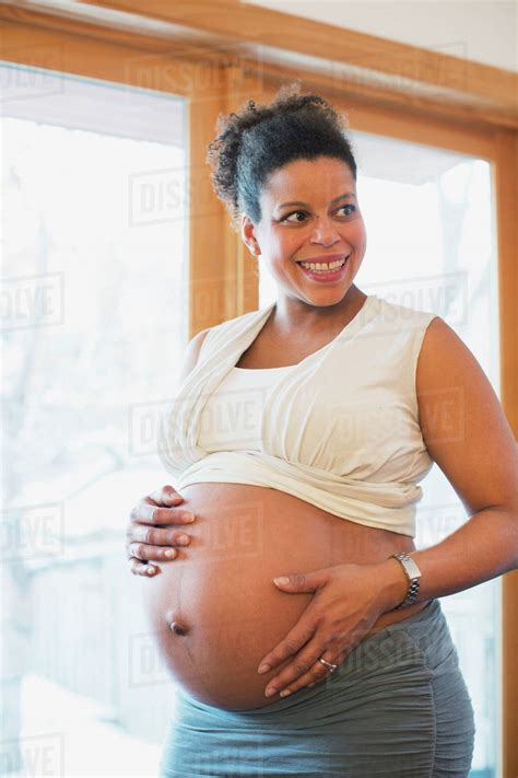 A Pregnant Woman Holds Her Bare Belly At The End Of Pregnancy In The Window Light Toronto