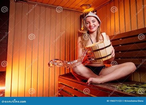 Beautiful Girl With Yellow Broom On Wooden Bench At Sauna In Steam Room