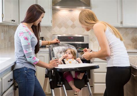 Two Young Women Feeding Little Girl In Highchair Stock Photo Image