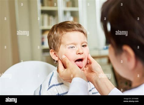 Female Doctor Examines Throat And Tongue In Child With Tonsillitis Or