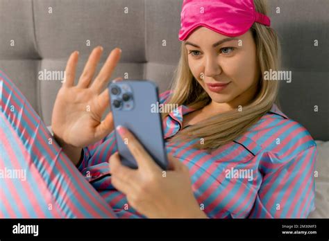 Portrait Of Beautiful Joyful Woman In Pajamas Using Mobile Phone And